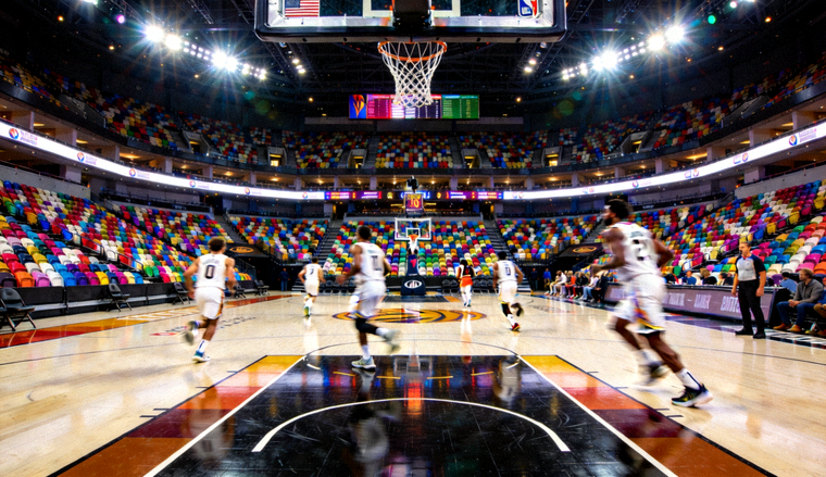 NBA篮球比赛场地全景，球员在场上跑位，观众席灯光璀璨